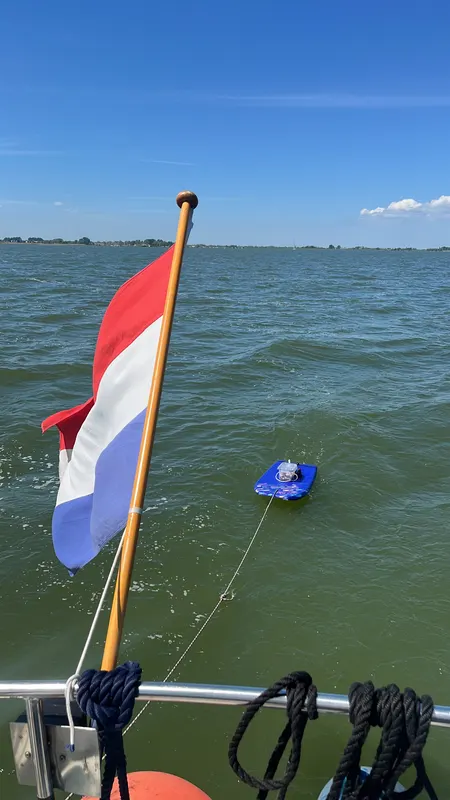 The prototype towed behind a boat on the Markermeer, Dutch flag in the foreground